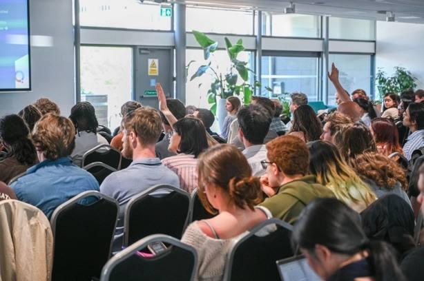 A packed session with an attendee raising a hand to ask a question